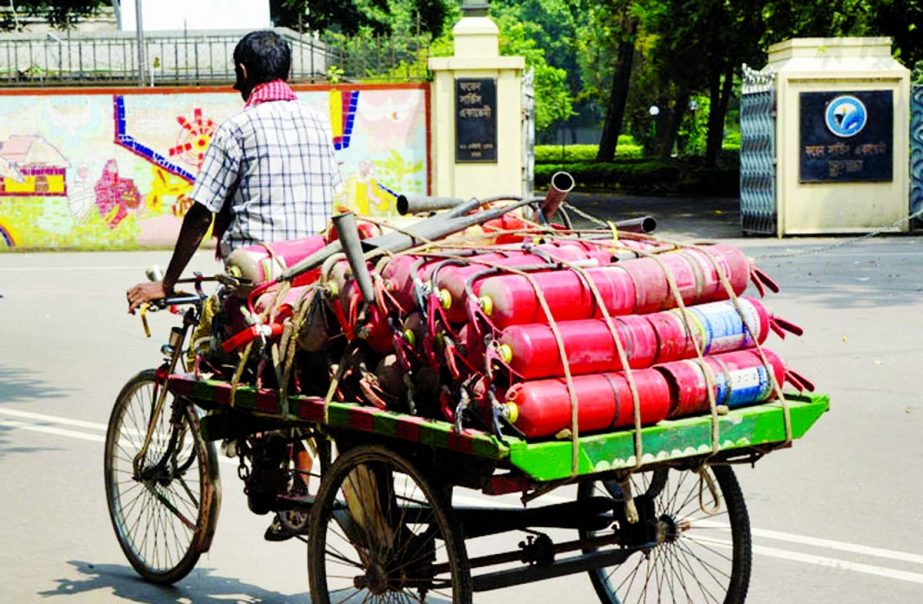 A rickshaw van driver carries fire extinguishers to the Mintu Road in the capital on Tuesday amid incidents of fire. NN photo