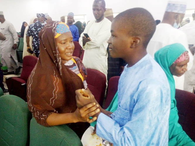 A mother reacts as she holds on to her son, one of the students from Tegina's Salihu Tanko Islamic School who were abducted three months ago by gunmen, at the government house after their release, in Minna, Nigeria on Friday.