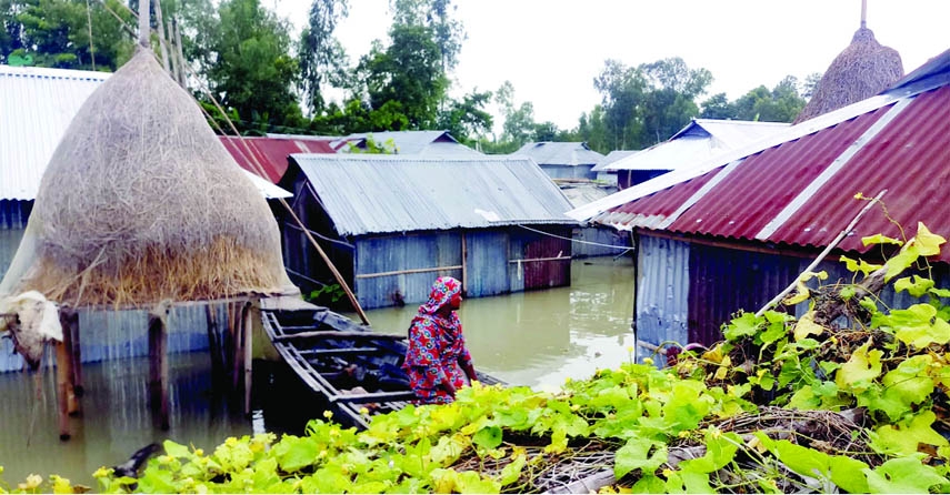 Desperation in sight, a housewife sitting on a boat looks at her belongings left in a flood-affected home at Kalatipara village under Hatia Union of Ulipur Upazila in Kurigram. The photo was taken yesterday.