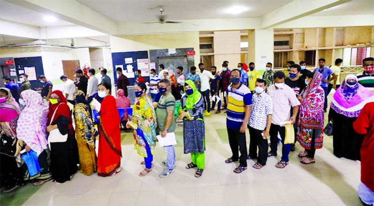 People stand in a long queue at the Mughda General Hospital in the capital on Sunday to receive corona vaccine jabs.