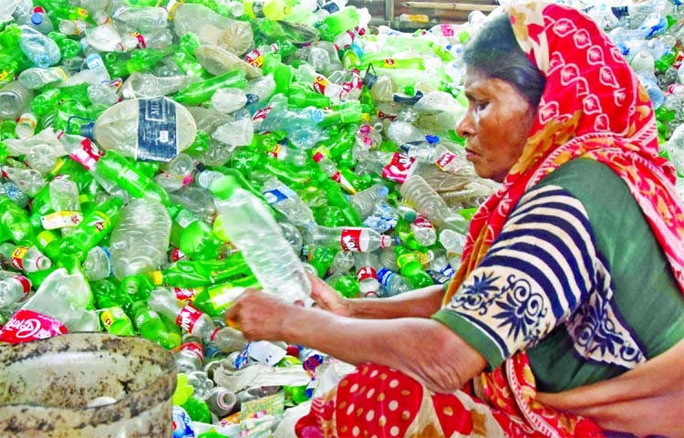 A woman handles a pile of thrown away plastic bottles at Kamrangirchar in the capital on Monday.