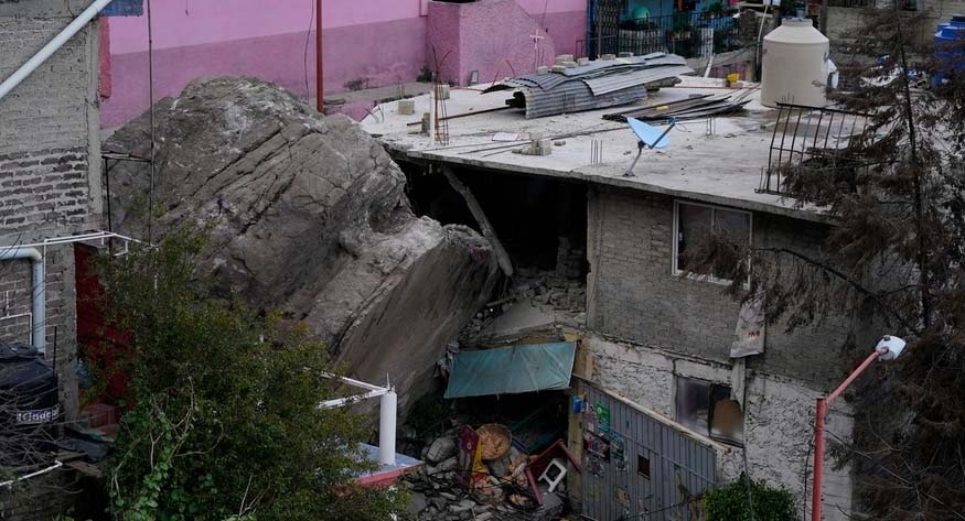 A boulder that plunged from a mountainside rests among homes in Tlalnepantla, on the outskirts of Mexico City, when a mountain gave way on Sept. 10, 2021.