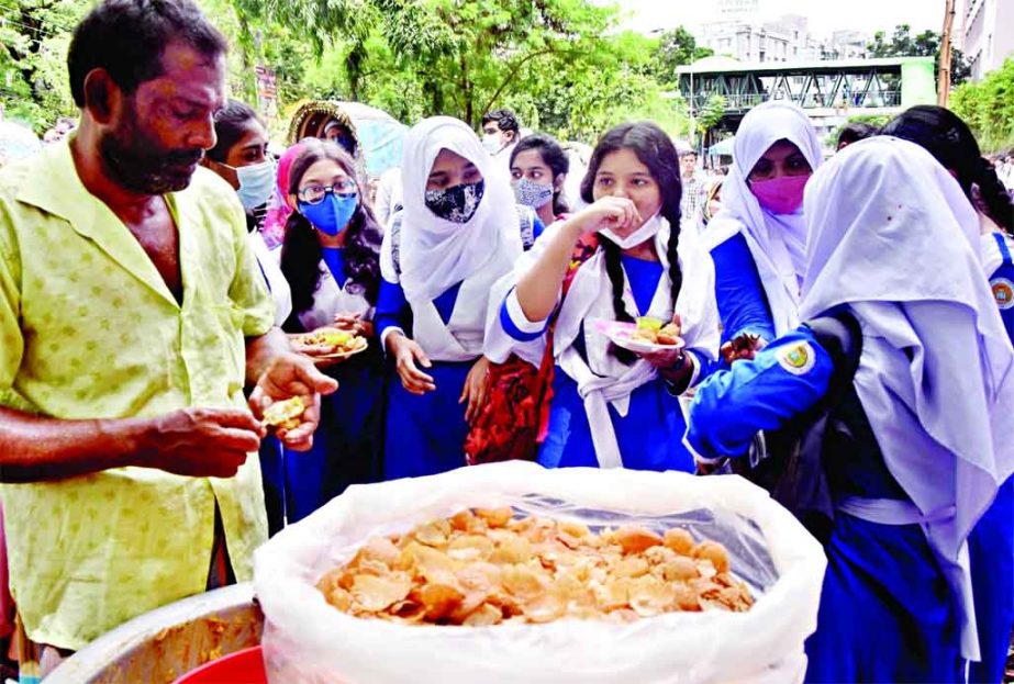 Students express joy while gobbling fuchka, the most popular street food in Dhaka, in front of Motijheel Ideal School in the capital on Monday following reopening of educational institutions across the country. NN photo
