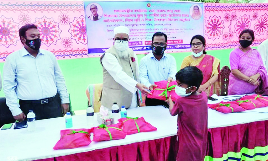 Manikganj Deputy Commissioner Muhammad Abdul Latif as the chief guest hands gifts provided by the Prime Minister's Office to the students on Tuesday. Shibalaya Upazila Nirbahi Officer Jasmin Sultana presided over the distribution function organized by Up