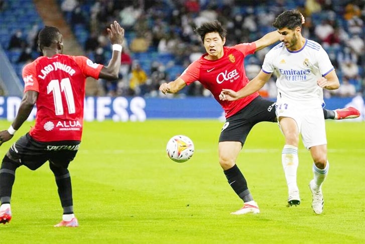 Real Madrid's Marco Asensio (right) and Mallorca's Lee Kang-In battle for the ball as Mallorca's Lago Junior (left) watches during a Spanish La Liga soccer match at the Bernabeu stadium in Madrid, Spain on Wednesday.