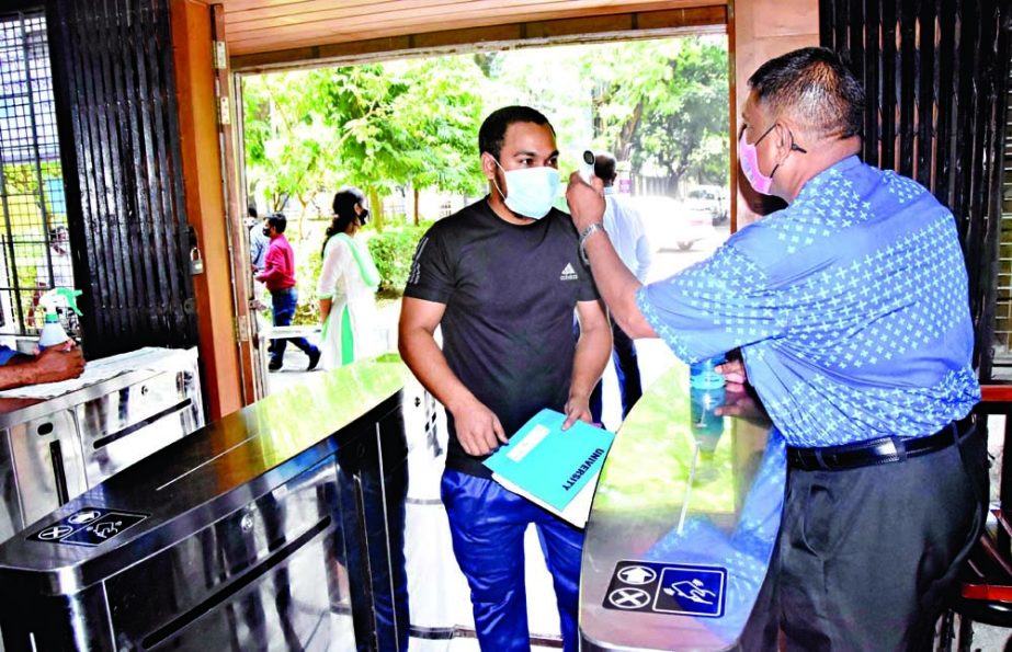 A student has his body temperature checked before entering the central library of Dhaka University on Monday amid falling Covid-19 infections in the country. NN photo