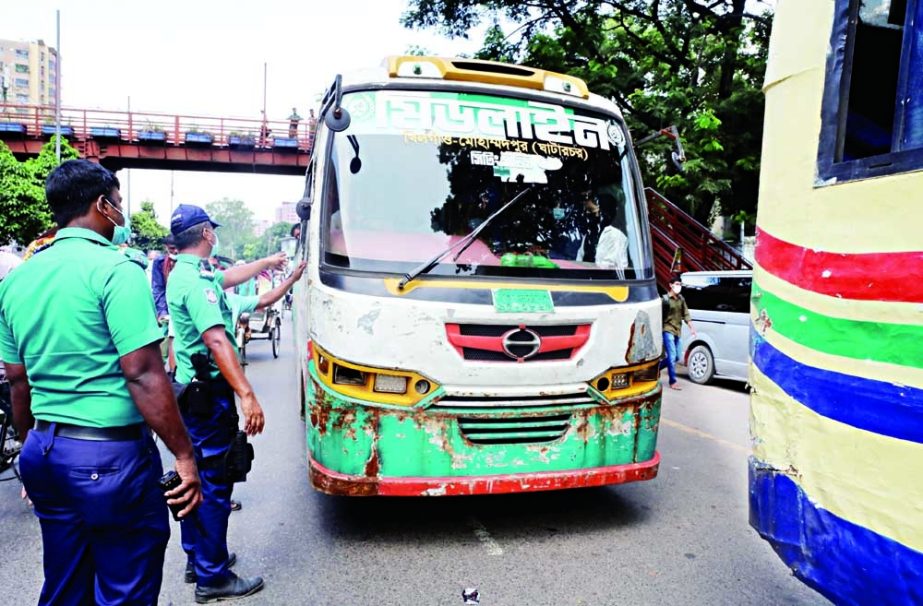 Traffic police halt a passenger bus on a road in the capital's Motijheel area on Sunday to check fitness and other papers during a joint drive by the BRTA and the DSCC NN photo