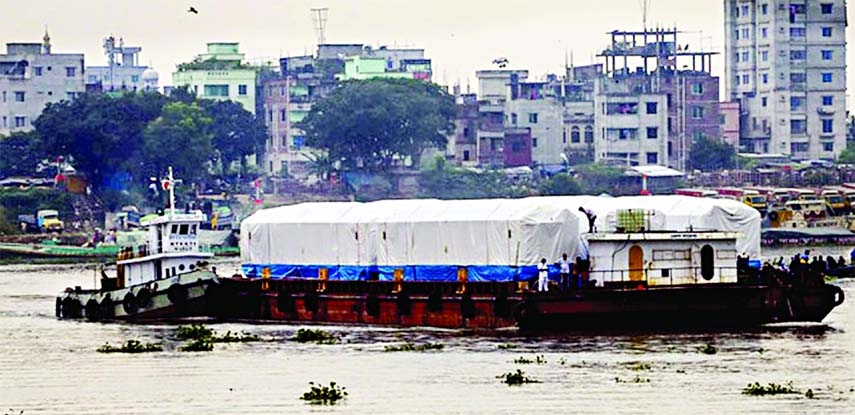 A berge which carried the 5th train section of Dhaka Metro Rail (covered with white cloth) reaches Diabari Mass Transit Ltd crossing Turag River on Wednesday.