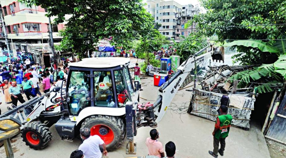 A bulldozer of the Dhaka North City Corporation (DNCC) knocks down illegal establishment on Sunday morning to recover the Rupnagar canal in the capital. NN photo