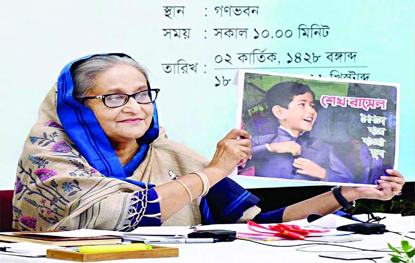 Prime Minister Sheikh Hasina unveils the cover of book titled "Sheikh Russel: Shoishobe Jhore Jawa Phul" (Sheikh Russel, a fallen flower in childhood) at a function organized by the Sheikh Russel Roller Skating Federation in the capital through video co