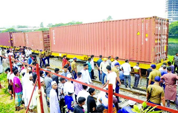 A large crowd gather at the site of derailed freight train in Dhaka's Kawran Bazar area on Friday.