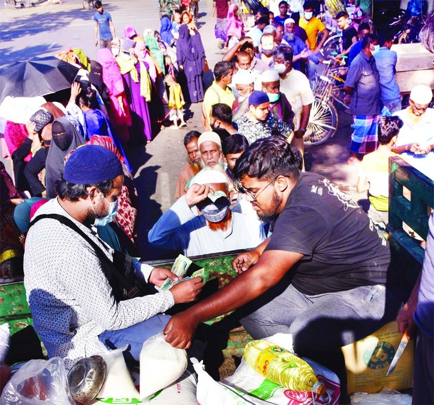 People stand in long queues at AGB colony area in the capital on Sunday to purchase OMS products from a TCB truck as price hike has made essentials dearer.