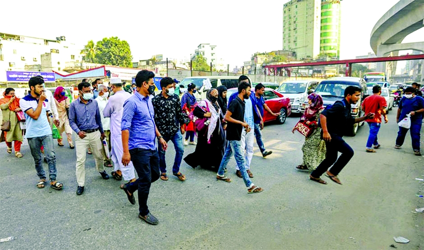 Pedestrians cross the street in Dhaka's Farmgate ignoring a sign to use footbridges. This photo was taken on Friday.