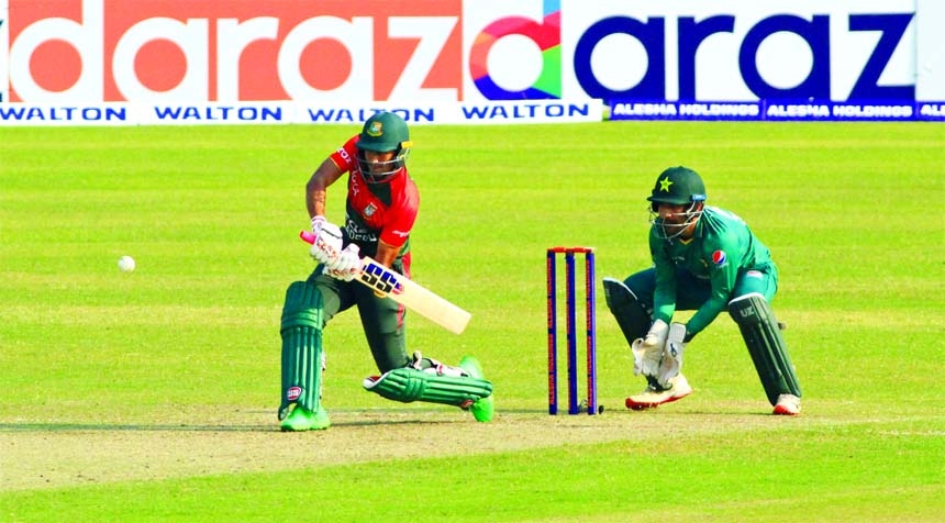 Bangladeshi opener Mohammad Naim Sheikh drives the ball as Pakistani wicket keeper Sarfaraj Ahmed looks on at their 3rd T-20 match in Dhaka on Monday.