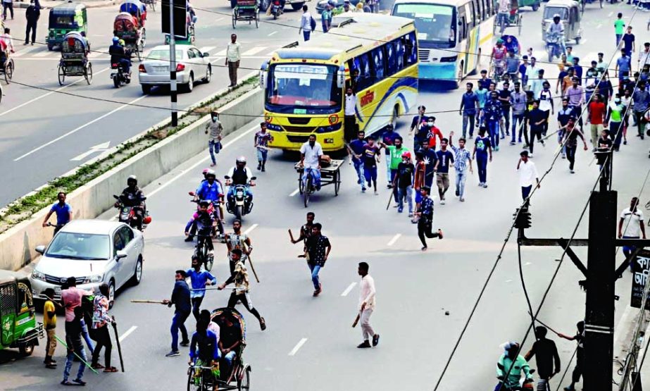 A group of stick wielding people chase garment workers of IDS group as they were blocking roads at Mirpur-13 area in the capital on Tuesday for arrear salary. NN photo