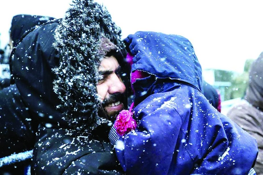 A migrant holds his child as he waits to get meal during a snowfall outside a logistics center at the checkpoint "Kuznitsa" at the Belarus-Poland border near Grodno, Belarus on Tuesday. Agency photo