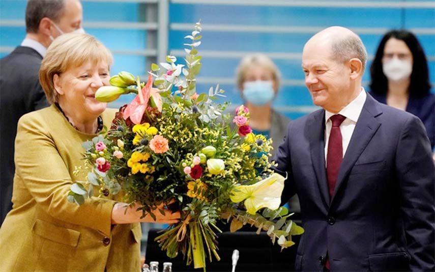 Acting German Chancellor Angela Merkel receives a bouquet from acting German Finance Minister Olaf Scholz prior to the weekly cabinet meeting at the Chancellery in Berlin, Germany on Wednesday.