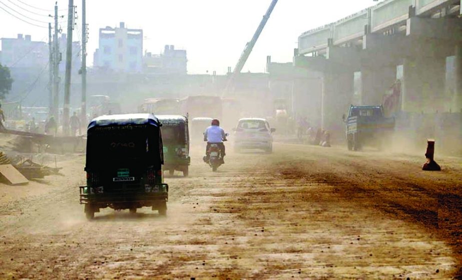 Dust covers Dhaka's Kalshi area as road construction work is going on beneath of an under-construction flyover. NN photo