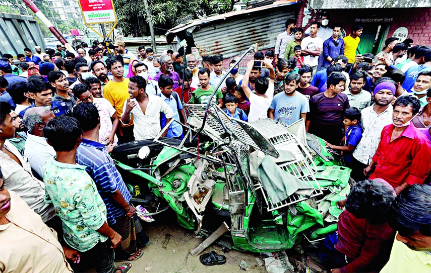 Onlookers stand next to a smashed CNG autorickshaw after it was hit by a speeding train at Khulshi in Chattogram on Saturday.