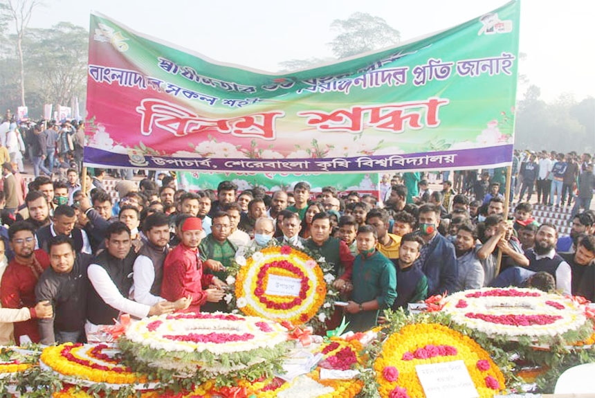 Teachers and employees of Sher-e-Bangla Agricultural University place floral wreaths at Savar National Memorial on Thursday marking Victory Day.