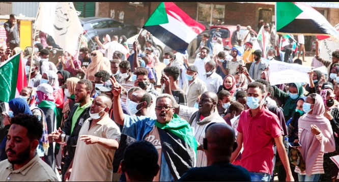 Sudanese demonstrators raise national flags and banners as they rally against the military chief who launched an October 25 coup followed by a bloody crackdown, in the northern part of the capital Khartoum
