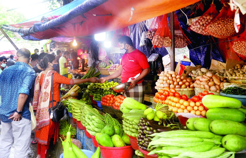 Vendors sell winter vegetables at a kitchen market by turning on lights even in day hours amid dense fog in the capital. This photo was taken from Hatirpool Bazar area on Wednesday.