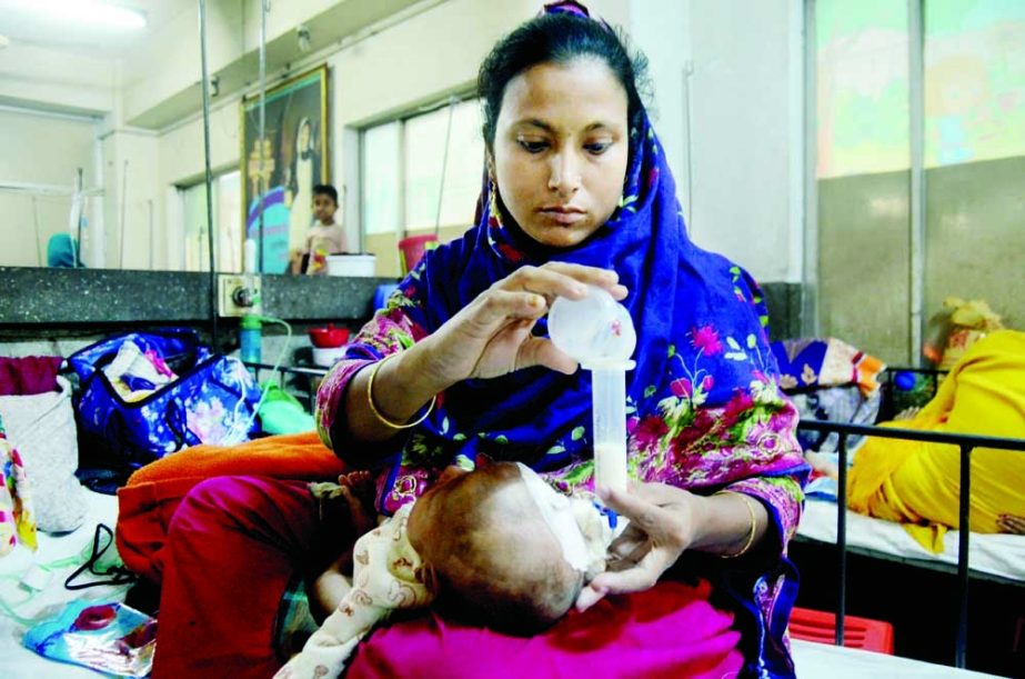 A woman feeds her baby, who is suffering from respiratory disease, with a nasal cannula at Dhaka Shishu (Children Hospital) on Thursday. NN photo