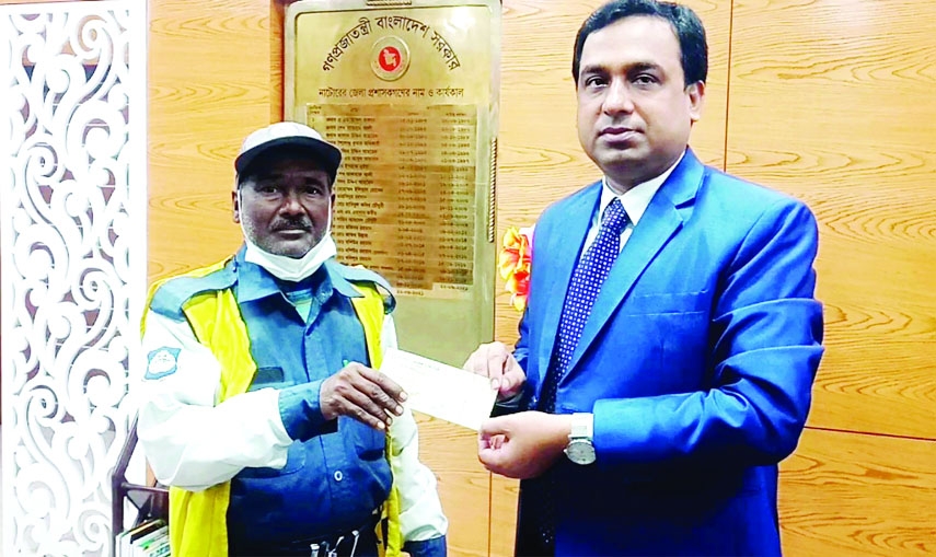 BARAIGRAM (Natore) : Md. Shamim Ahmed, DC, Natore presents a cheque of Tk 10 thousand to Babul Hossain, a volunteer community police at his office on Thursday.