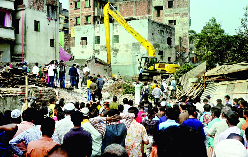 A BIWTA bulldozer conducts an eviction drive demolishing unauthorised structures at Kamrangirchar area on the bank of the Buriganga River on Monday.