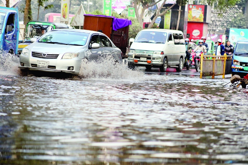 Vehicles ply on a waterlogged road near the SAARC fountain in the capital's Kawran Bazar on Monday as cracks developed its a wall.