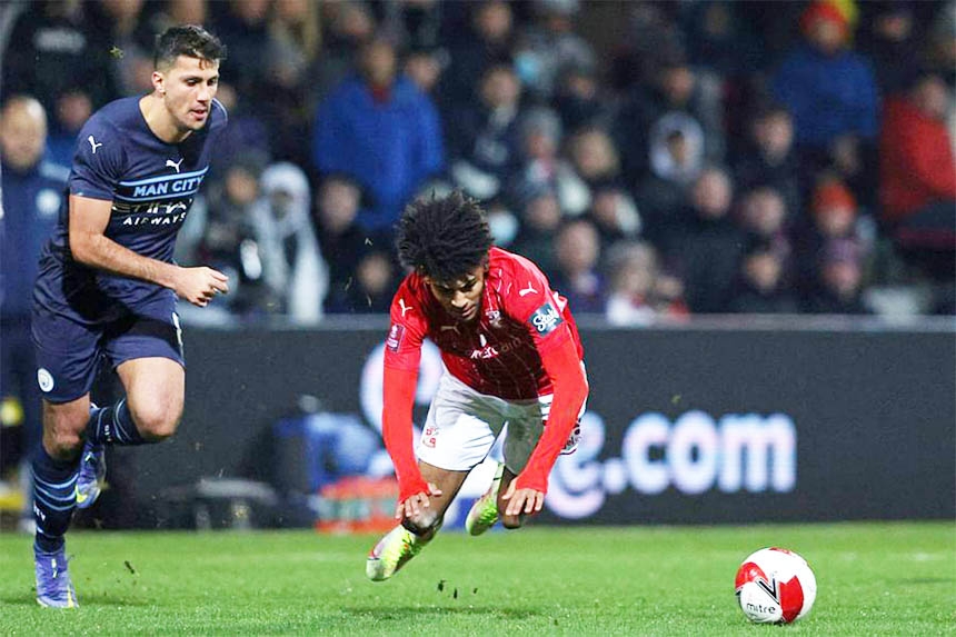 Swindon Town's defender Kaine Kesler Hayden (center) is fouled by Manchester City's midfielder Rodri (left) during the English FA Cup 3rd round football match at County Ground, Swindon in western England on Friday.