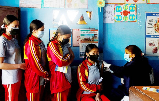 Students wait in a queue as their friend receives a dose of the Moderna vaccine, at their school during a vaccination drive for children in Bhaktapur, Nepal on Sunday.
