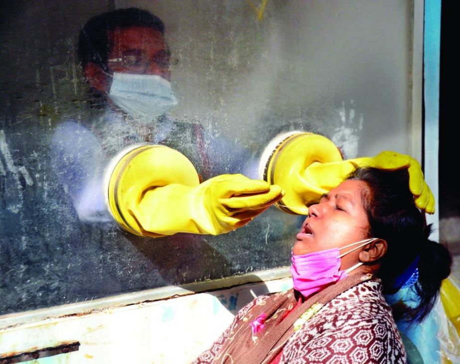 A health worker collects a swab of a woman during a coronavirus test at a health centre in the capital's Purana Paltan area on Tuesday amid rapid surge in coronavirus cases in Dhaka. NN photo