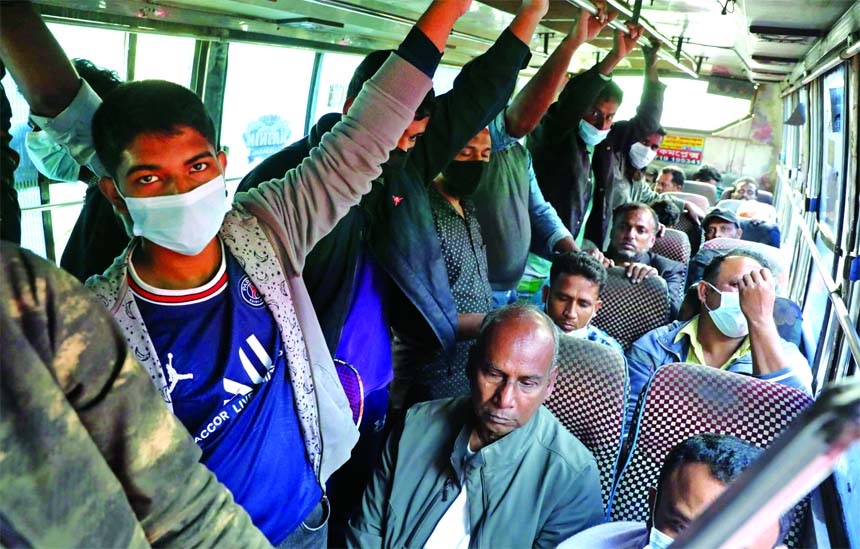 Passengers board on a bus huddled together beyond its seating capacity defying health norms amid the surge of Omicron infection. This photo was taken from Jatrabari area in the capital on Saturday.