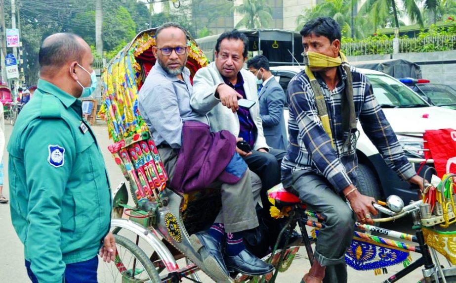 A police personnel stops a rickshaw at the capital's Motijheel area on Saturday, as its passengers were not wearing masks defying the government instruction. NN photo