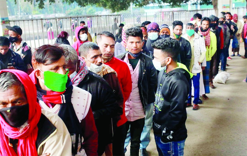 Passengers stand in a long queue at Kamalapur Railway Station on Sunday flouting social distancing norms despite some health guidelines issued by the government to prevent the new variant of coronavirus 'Omicron'.