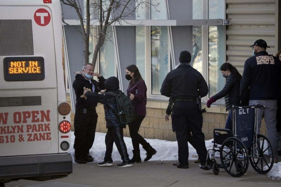 Children are escorted from the building and board a bus Tuesday, Feb. 1, 2022, at the South Education Center, an alternative school in Richfield, Minn. Two students were shot, one of them fatally, outside the suburban Minneapolis school.