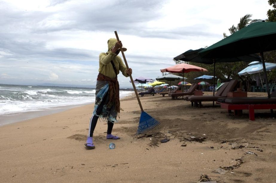 A woman sweeps rubbish at Kuta beach, Bali, Indonesia on Friday, Feb. 4, 2022.