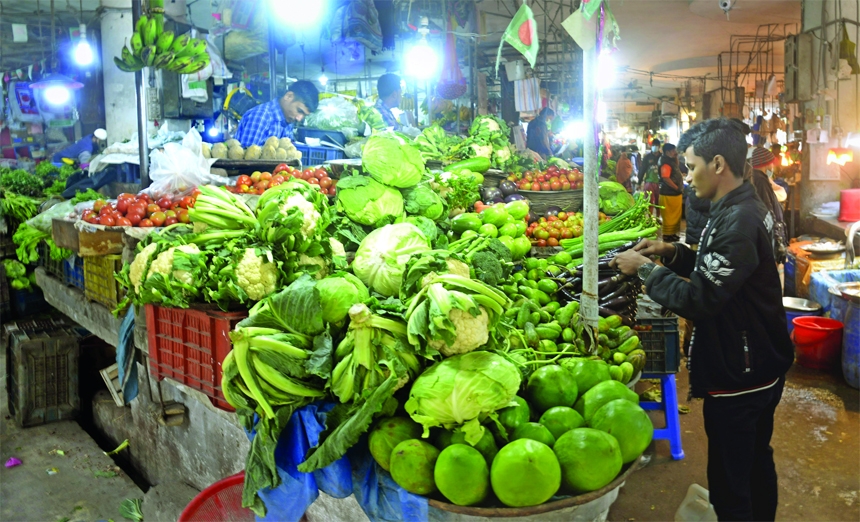 A man stands in front of a vegetables shop buy at BUET Bazar in the capital on Friday. The price of daily essentials was beyond the purchasing capacity of the customers.