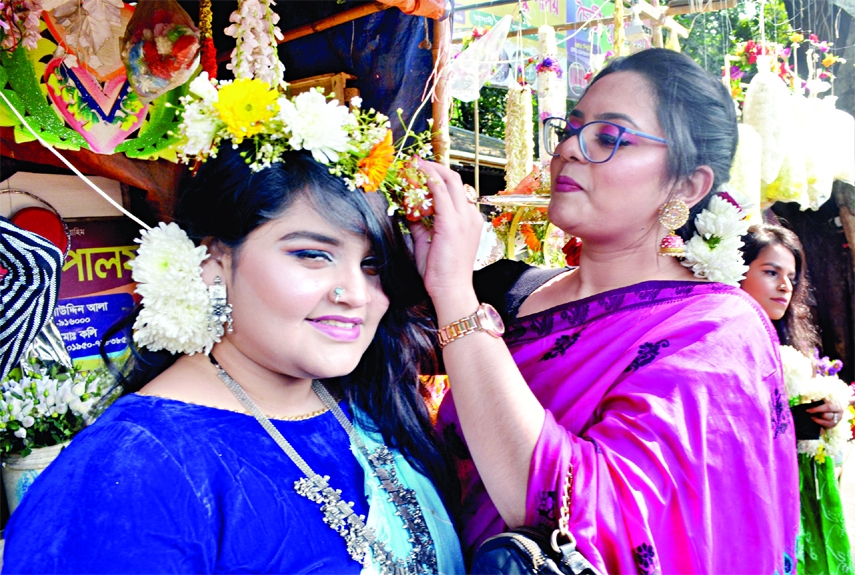 A woman adorns the latter's head with floral crown ahead of Pahela Falgun and Valentine's Day to be celebrated today (on Monday). This photo w3as taken from in front of a flower shop in the capital on Sunday.