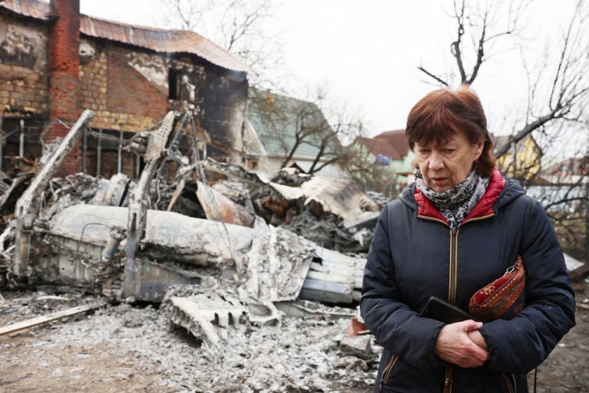 A woman walks around the wreckage of an unidentified aircraft that crashed into a house in Kyiv, Ukraine.