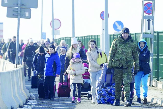 A Polish border guard assists refugees from Ukraine as they arrive to Poland at the Korczowa border crossing, Poland, on Saturday.