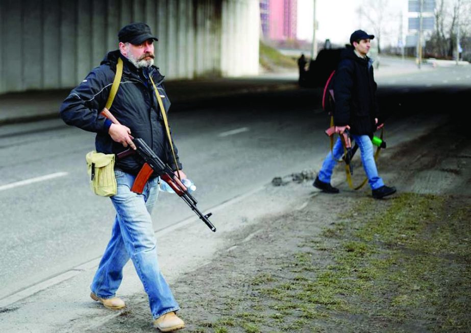 Ukrainian volunteers, one holding an AK-47 rifle, protect a main road leading into Kyiv, Ukraine, on Saturday. Agency photo