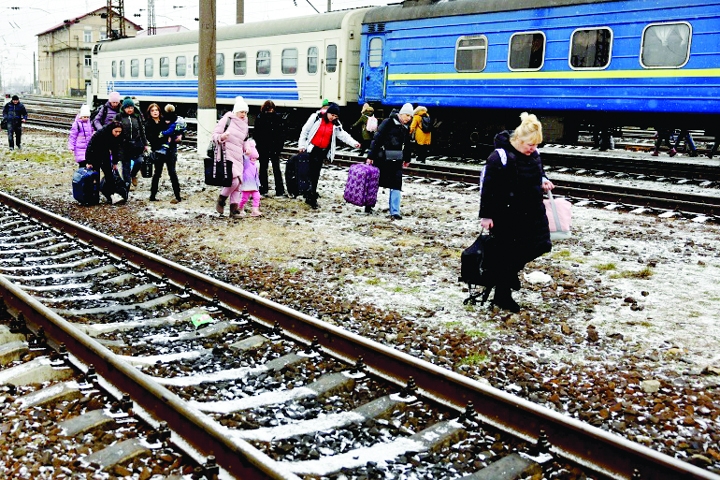People walk with their luggage between the railway tracks in Lviv, Ukraine [Kai PfaffenbachReuters]