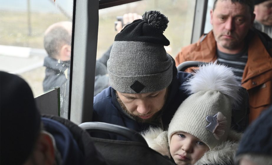 Refugees fleeing fleeing the military operation zone from the Mariupol area of Ukraine sit in a bus as they arrive at the border crossing in Veselo-Voznesenka, Russia, Monday, March 7, 2022.