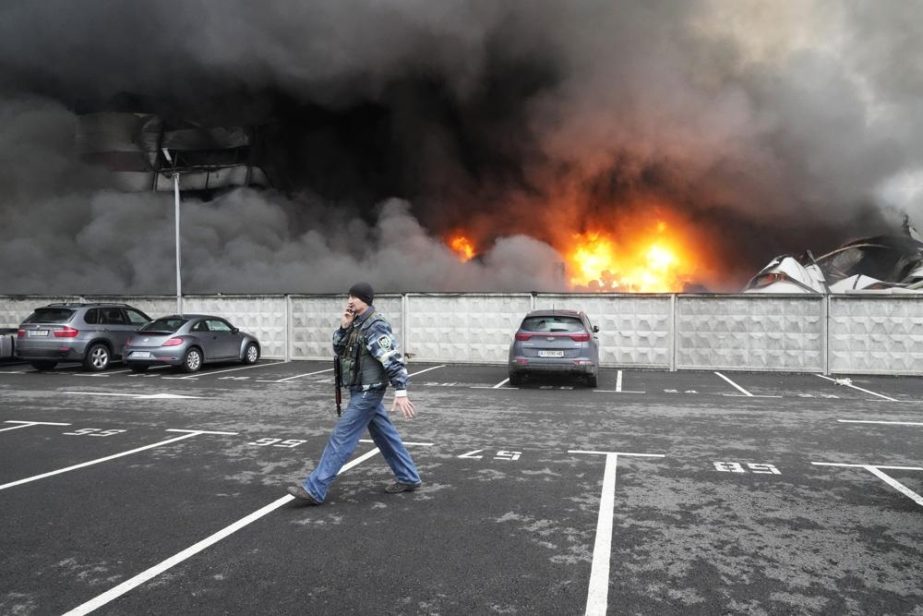 A Ukrainian serviceman walks past as fire and smoke rises over a damaged logistic center after shelling in Kyiv, Ukraine. File photo