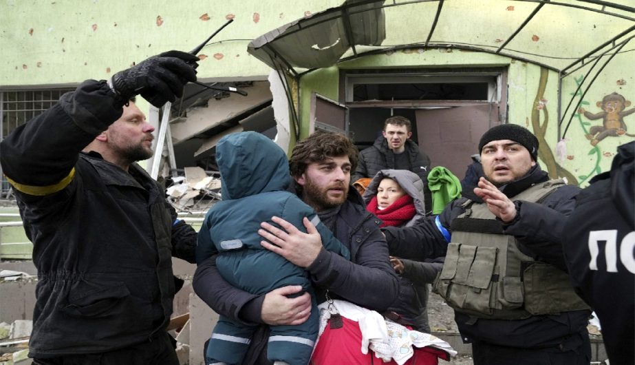 A man carries his child away from a damaged maternity hospital in Mariupol, Ukraine, Wednesday, March 9, 2022.