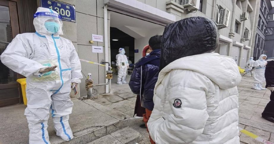 A worker wearing a protective suit speaks to residents in a neighborhood in Changchun in northeastern China's Jilin Province, Friday, March 11, 2022.