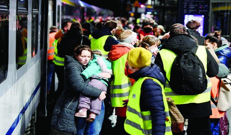 A woman carries a child after arriving on a train from Przemysl, Poland, at Berlin's central station, after fleeing Russia's invasion of Ukraine, in Berlin, Germany on Friday. Agency photo