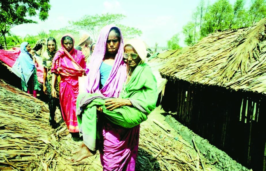 File Photo: A woman in Satkhira carries an elderly woman during Cyclone Aila.